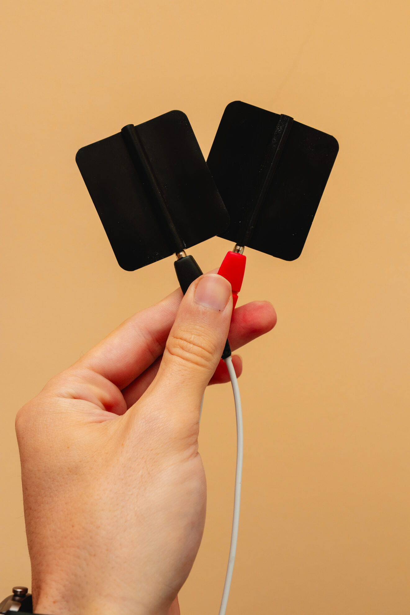 Hand hält zwei Elektroden der Frequenztherapie