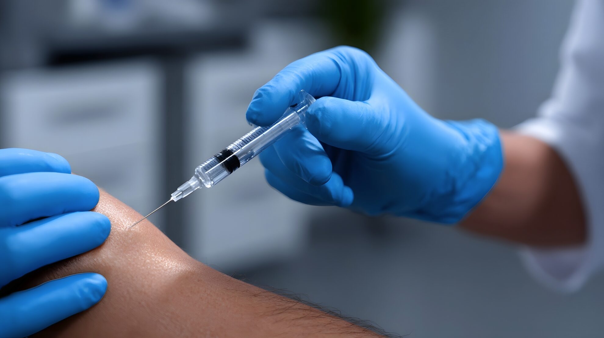 Nahaufnahme von Händen in Gummihandschuhen, die eine Injektion setzen